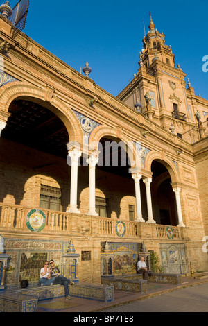 Touristen sitzen auf gefliesten Bänke & dekorative Bögen der "Provinz Alkoven / Nischen von Sevilla Plaza de España de Sevilla. Spanien Stockfoto