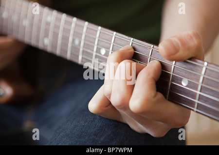 Junger Mann Playes Akkord auf der Gitarre Stockfoto