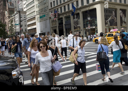 Es gibt immer eine Mischung aus Shopping, Touristen und New Yorker entlang der 5th Avenue in der 57th Street in New York City. Stockfoto