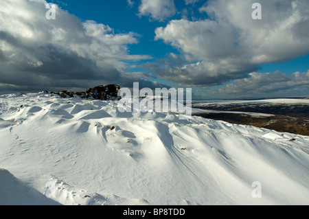 Winterschnee driftet auf Kinder Scout Plateau, Peak District, Derbyshire, England, Vereinigtes Königreich. Eine Gruppe von Wanderern Zuflucht hinter Felsen. Stockfoto