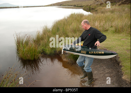 Männer Rennen mit Radio - kontrolliertes Modell Motorboote auf einem Teich, Wales UK Stockfoto