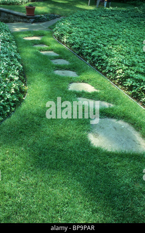 Stepping Steinweg in Rasen in Sonne und Schatten mit immergrünen Bodendecker Pachysandra, einem einladenden Anfang einer Reise Stockfoto