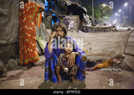 Ein Vater mit seinem Sohn in der Nacht vor ihrer Hütte in einem der Slums von Kalkutta, Indien. Stockfoto