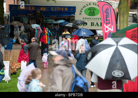 Besucher unter Sonnenschirmen im strömenden Regen auf Shrewsbury Flower Show 2010, Shropshire, UK Stockfoto