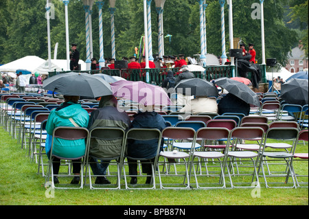 Besucher nach Shrewsbury Flower Show anhören ein Trommler-und Pfeiferkorps unter Sonnenschirmen, Shropshire, UK Stockfoto