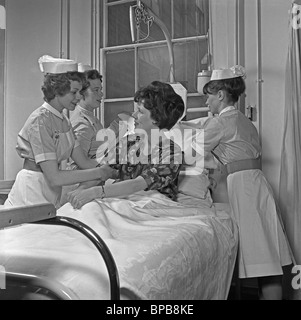 Krankenhaus Krankenschwestern versammelten sich um einen Patienten im Bett einstellen ihr Kissen, ca. 1960 Stockfoto