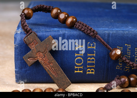 Alte blaue Bibel und Holzkreuz auf Gebet Rosenkranz Stockfoto