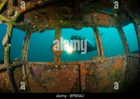 Ein Taucher erkunden das Wrack von einem kleinen Schlepper Boot im Hafen von Sabang, Pulau Weh, Sumatra, Indonesien. Stockfoto