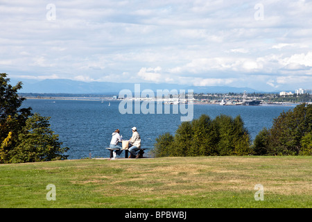 paar genießen Sie al-Fresco-Picknick im Park mit Blick auf blauem Wasser & entfernten Marine Installation des Port of Everett Washington Stockfoto