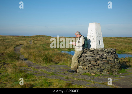 Walker gegen den trigonometrischen Punkt auf Black Hill, Pennine Way, West Yorkshire, England UK Stockfoto