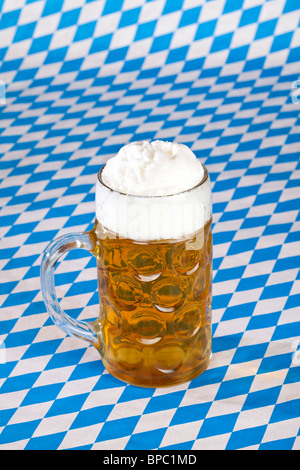 Volle Oktoberfest Bierkrug und bayerische Flagge im Hintergrund Stockfoto