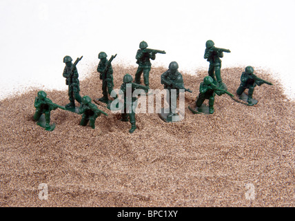 Eine Gruppe von kleinen Kunststoff-grüne Armee Männer auf einen Sandhaufen vor einem weißen Hintergrund eingerichtet. Stockfoto