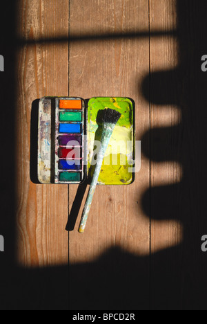Antike verwendet Künstler Aquarellpinsel Paintbox und Farbe auf eine Holzoberfläche mit tiefen geformte Schatten. Stockfoto