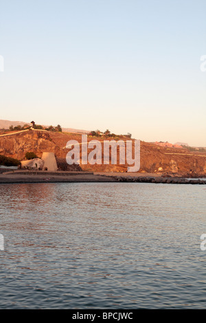 Die Klippen und Kalkofen am Ende der Playa San Juan mit das Abama resort am Horizont und klarer blauen Himmel und ruhiger See Tener Stockfoto