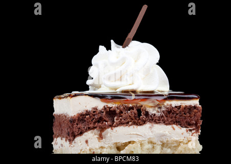 Eine Nahaufnahme einer Schicht Kuchen mit dunkler Schokolade und einer helleren Schwammschicht, getrennt und mit cremeweißem Zuckerguss belegt. Das Oberteil ist mit einem Wirbel Peitsche garniert Stockfoto