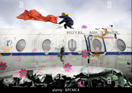 Ein Künstler schmückt ein altes Flugzeug der RAF mit Blumen in The Trash Stadtgebiet auf dem Glastonbury Festival-Gelände Pilton UK Stockfoto