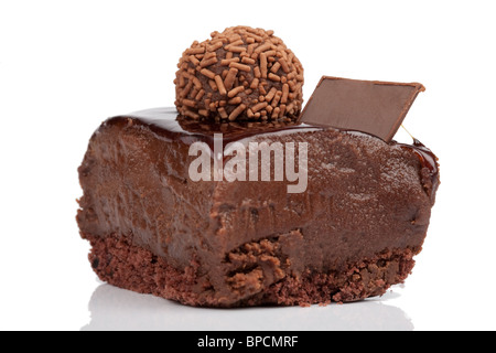Eine Nahaufnahme einer einzelnen Scheibe reichhaltigen Schokoladenkuchen mit einer glänzenden Schokoladenglasur darüber. Der Kuchen besteht aus einer dichten, feuchten Schokoladenmousse oder Ganache über einem bröckeligen Schokoladenkeks oder -Kuchen Stockfoto