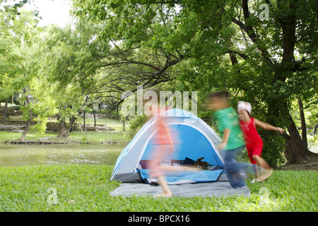 Kinder jagen einander um ein Zelt beim camping Stockfoto