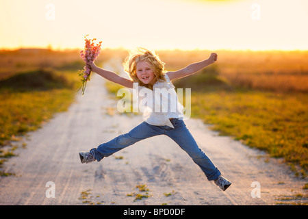 Junges Mädchen mit Blumen in die Luft springen Stockfoto