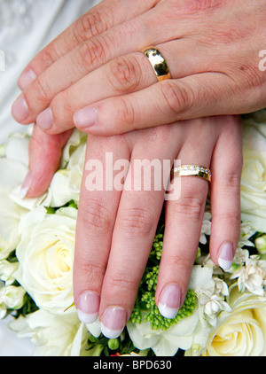 Mann und Womans Händen hielt über Blumenstrauß und Trauringe zeigen Stockfoto