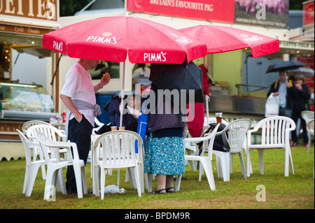 Besucher zu Shrewsbury Flower Show 2010 Unterschlupf vor Regen unter Sonnenschirmen, Shropshire, UK Stockfoto