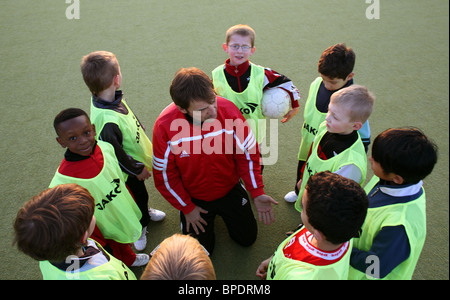 Ein Trainer im Gespräch mit Kindern im Fußball-Praxis, Berlin, Deutschland Stockfoto