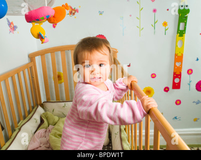 Gemischte Rassen Babymädchen stehen in Krippe Stockfoto