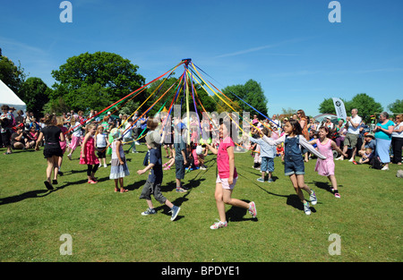 Junge Kindertanz runden ein Maibaum bei einem Dorffest in Rigmer in Sussex Stockfoto