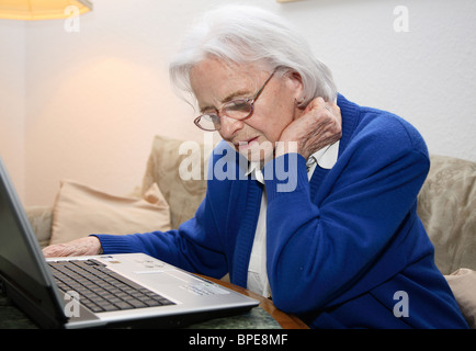 Ältere Frau, die einen Laptop betrachten Stockfoto