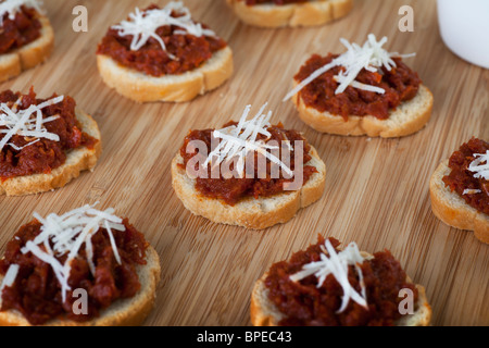 Frische hausgemachte sonnengetrocknete Tomaten Tapenade auf geröstetem Baguette belegt mit frisch geriebenem Käse. Stockfoto