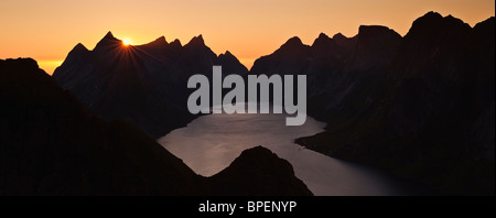 Sonnenuntergang hinter schroffen Berggipfel und Kjerkfjord von Reinebringen Peak, Reine, Lofoten Inseln, Norwegen Stockfoto