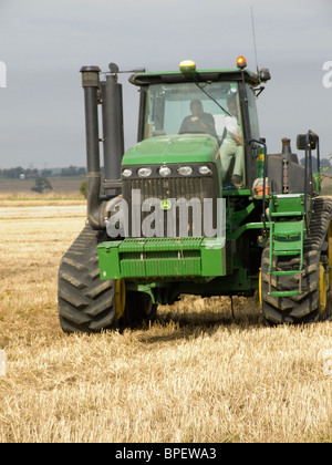 John Deere Kautschuk verfolgt Traktor in einem kürzlich geernteten Maisfeld bereit zum Pflügen der Erde aufbrechen Stockfoto