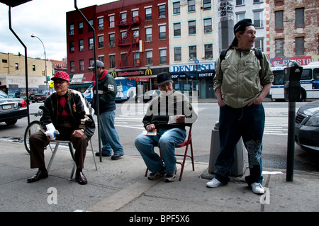 Gruppe von Männern sitzt auf dem Bürgersteig in East Harlem Stockfoto