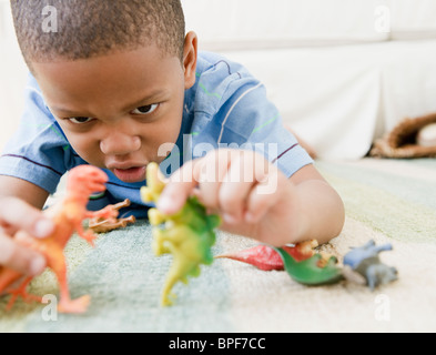 African American Boy auf Boden spielen mit Spielzeug Dinosaurier Stockfoto