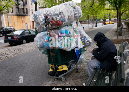 Obdachlose Menschen sitzen auf der Parkbank mit Trolley Recycling Blechdosen und Glasflaschen Stockfoto