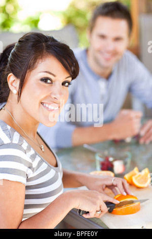 Hispanic Frau schneiden Orangen auf Terrasse Stockfoto