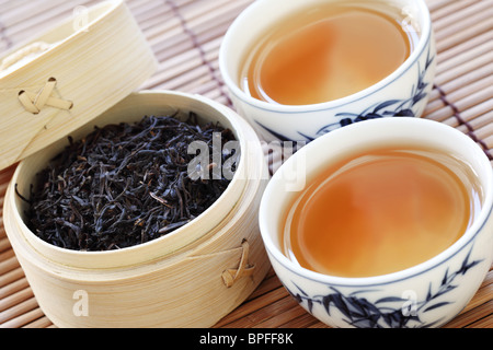 Schwarzer Tee in eine weiße Tasse mit einem Tee Blätter Stockfoto