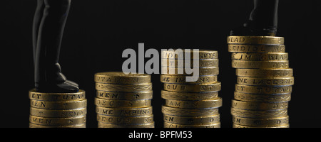 Zwei Figuren In schwarzen Anzügen, Stand am Anfang von ungleichen Pfähle der Pfund-Münzen Stockfoto