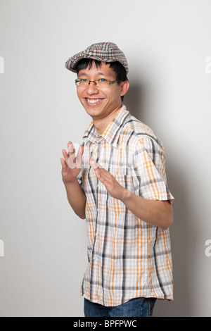 Fröhlicher junger Mann, der in die Hände klatscht, ein kariertes Hemd und eine karierte Mütze trägt. Stockfoto