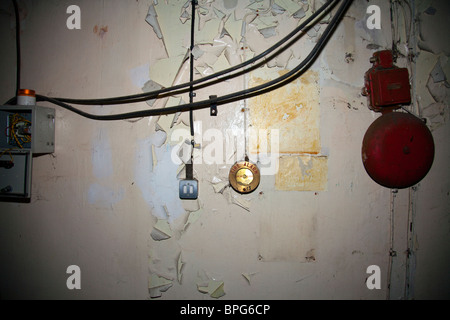 Alten Alarmglocke und schalten Sie zusammen ein Wand mit flockige Farbe in verlassenen Malz Brennofen in Louth, Lincolnshire Stockfoto