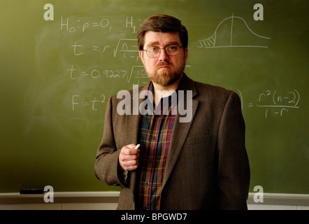 Math Professor oder Lehrer stehen in einem Klassenzimmer, statistischen Formel an grüne Tafel im Hintergrund. Stockfoto