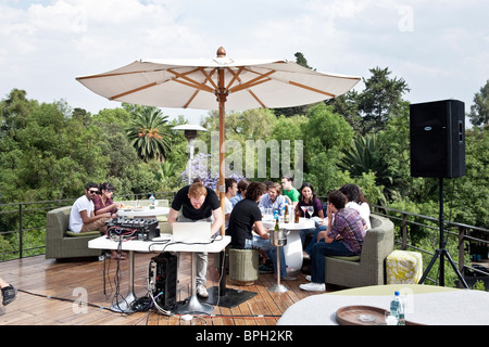 Deejay schwebt über Macbook wie Gruppen von attraktiven jungen, die Mexikaner bei einem Drink an trendigen entspannen, Rooftop Bar Hotel Condesa gehobene Stockfoto