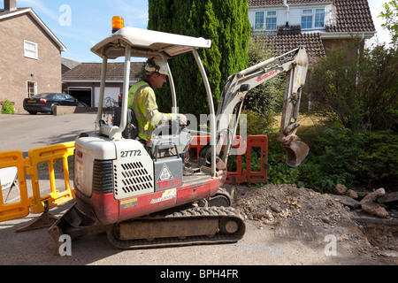 Arbeitnehmer mit einem Minibagger, ein Graben in der Straße Stockfoto