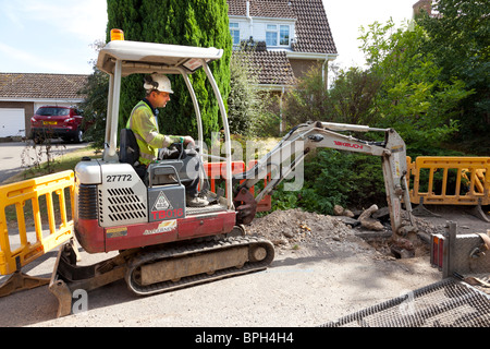 Arbeitnehmer mit einem Minibagger, ein Graben in der Straße Stockfoto