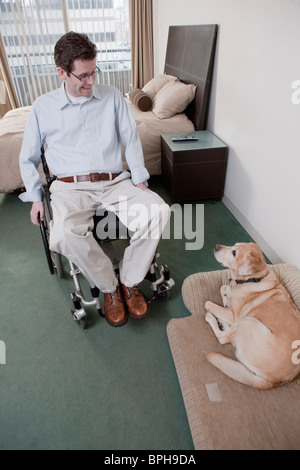 Mann in einem Rollstuhl mit einem Servicehund Stockfoto