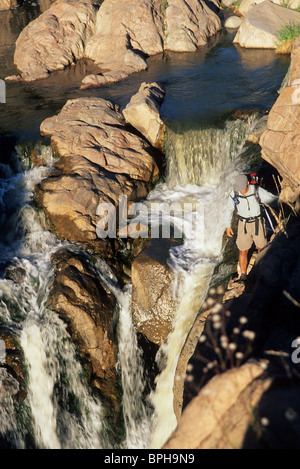 Mann sucht über Klippe zu Wasserfällen. Stockfoto