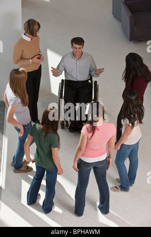 Lehrer mit Querschnittslähmung im Rollstuhl mit Schülern und ihren Müttern Stockfoto