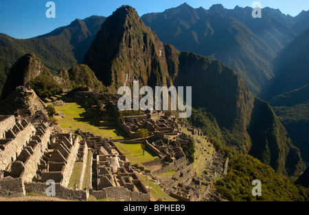 Touristen inmitten der komplizierten Steinarbeiten von zerstörten Gebäuden und Gartenterrassen an der alten Inka-Stadt Machu Picchu, Peru. Stockfoto