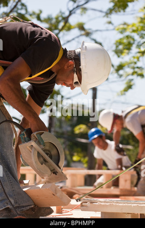 Tischler mit Kreissäge auf einer Baustelle mit Giebel Rahmen im Hintergrund Stockfoto