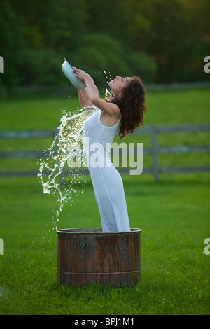 Junge Frau gießt Wasser über sich selbst außerhalb Stockfoto